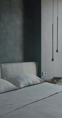 Gri duvarları, minimalist mobilyaları ve doğal ışığı olan modern yatak odası iç tasarımı. Yatak gıcır gıcır beyaz çarşaflarla yapılır ve şık bir lamba zarafet katar. Rahatlama ve dinlenme.