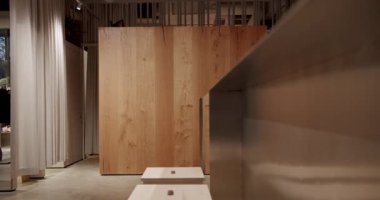 Modern giyim mağazasının içinde uygun odalar var. Meşe ahşap kaplama, beton zemin ve nötr renk paleti olan minimalist tasarım. Tezgahın yanındaki tabureler. Doğal ışık. Sıcak, davetkar atmosfer.