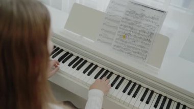 Müzik dersi veren genç bir müzisyen. Sessiz bir kişi dairesinde otururken piyano çalışır. Ev müziği stüdyosu kadını. Müzik eğitimi. Eller piyano tuşlarına basıyor..