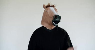 At maskesi takan bir adam elleri pürüzsüz beyaz bir arka planda hareket eder. Anonimlik, sürrealizm ve kimlikle ilgili kavramlar için idealdir. Beyaz Arkaplanda At Maskeli Adam Hareketleri