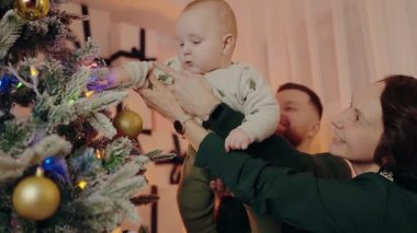 Mutlu bir aile ve bebek birlikte Noel ağacı süslüyorlar. Tatil sezonunu neşe, sevgi ve beraberlikle kutluyoruz. Aile Noel 'i birlikte kutluyor Tatiller için