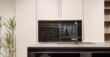 Modern beyaz ahşap mutfak mobilyası. Zarif, rahat ve Minimalist Ev. Modern siyah lavabosu olan yerli mutfak. Minimalist yemek masası olan modern mutfak odası. Modern Minimalist Ev.