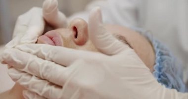 Yetenekli bir estetisyen kadın müşterinin parlak ve modern bir klinikte yüzünü inceliyor. Profesyonel Estetikçi Kadın Müşteri Cildini Nazikçe İnceledi