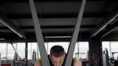 Çağdaş bir spor salonundaki kablo makinesinde egzersiz yaparken yoğun bir şekilde odaklanan genç bir erkek azim ve fitness hedefleri sergiliyor. Modern Spor Salonunda Kablo Makinesinde Çalışan Odaklanmış Genç Adam