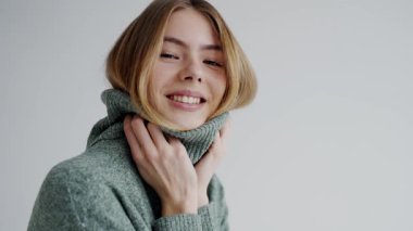 Parlak bir gülüşü olan, yumuşak yeşil balıkçı yaka kazak giyen, minimalist bir ortamda sıcaklık ve mutluluk saçan ışıl ışıl genç bir kadın. Samimi Yeşil Süveterli Genç Kadın Düşünceli Poz Veriyor