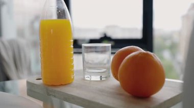 Bir şişe taze portakal suyu ve iki büyük portakal bir cam tarafından ahşap bir tepsiye konur, sağlık ve sadelik duyguları uyandırır. Taze Portakal Suyu ve Portakallar Tahta Tepside Pencere kenarında