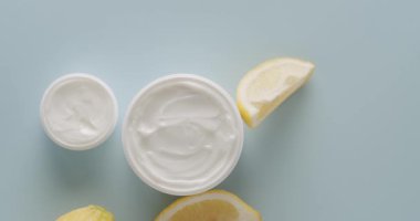 Kozmetik için limon meyveli beyaz şişe ve tüpler stüdyoda açık mavi arka planda. Saç ve cilt bakımı için doğal kozmetik ürünleri. Farklı kozmetik şişelerden oluşan bir grup. Üst görünüm.