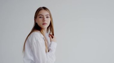 Sıradan beyaz gömlekli beyaz bir kadının portresi sade, açık arkaplana hafifçe gülümsüyor. Gençlik, güzellik ve basitlik temaları için mükemmel..