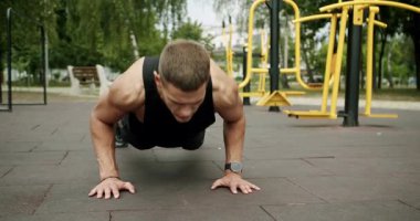 Atletik vücutlu bir adam sabah sporunu dışarıda yapar ve şınav çeker. Sportif adam spor sahasında kol kaslarını çalıştırıyor ve eğitiyor. Spor, sağlık hizmetleri. Güç, motivasyon. Açık hava spor salonu