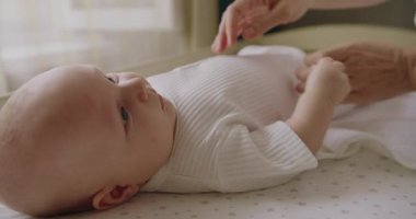 Anne kadın, bebek beşikteki güzel bebeğine nazik bir masaj yapıyor. Gülümseyen ve küçük bebeğiyle iletişim kuran mutlu genç bir anne. Anne oğluna yatakta masaj yapıyor..