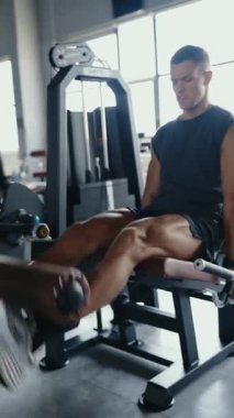 Odaklanmış bir adam spor salonunda bacak uzatma makinesiyle egzersiz yapıyor, daha düşük vücut gücü ve zindelik üzerinde çalışıyor. Jimnastik Salonunda Çalışan Adam Dikey Güç Eğitimi için Bacak Uzatma Makinesi Kullanıyor