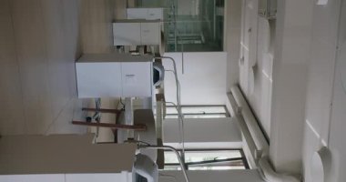 Modern ofis içi parlak beyaz sandalyeler ve minimalist çalışma alanı manzarası. Geniş pencereler doğal ışık sağlıyor ve davetkar bir atmosfer yaratıyor. Dikey video.