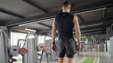 İyi donanımlı modern bir spor salonunda yoğun bir antrenmandan sonra dinlenmiş, kendine güvenen genç bir adam sağlıklı bir yaşam tarzı ve zindelik motivasyonu sergiliyor. Formda Genç Adam Antrenman yapıyor.