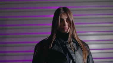 Uzun kahverengi saçlı genç kadın model renkli arka planda poz veriyor. Canlı neon renkli ışıklarla aydınlatılmış baştan çıkarıcı bir kadının portresi. Kameraya bakan güzel bir kızın portresi.