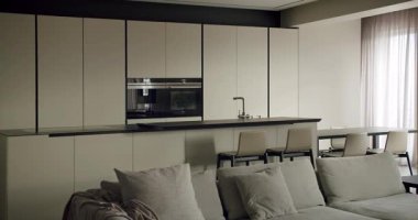 Zarif bir minimalist mutfak ve oturma odası iç mimarisi, nötr tonlarla çağdaş tasarımı gösteriyor. Minimalist Tasarımlı Modern Mutfak ve Oturma Odası