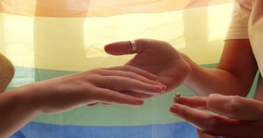 Kız sevgilisinin eline nişan yüzüğünü takıyordu, Lgbt bayrağında romantik bir kutlamanın tadını çıkarıyordu. Mutlu lezbiyen çift. Sevgi. LGBT hakları, lezbiyen ailesi. Yaşam tarzı ve ilişkiler.