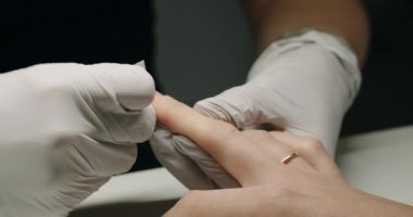 Manikürcü, manikürcüde, tırnak makası ile çivi işleyen bir öğretmenin gözetiminde manikür makinesi kullanarak bir kadının tırnak etlerini tedavi eder. Güzellik salonunda manikür. Çivi uzantısı.