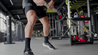 Modern Spor Salonunda Halter Egzersizleri Yapan Formda Genç Adam. Odaklanmış bir adam halter ile uğraşır, halter kullanarak çeşitli fitness ekipmanlarıyla dolu geniş bir spor salonunda..