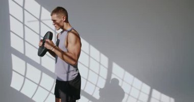 Atletik Genç Adam Modern Estetik ile Stüdyoda Egzersiz Yapıyor. Atletik erkek, iyi aydınlatılmış bir stüdyoda spor yapıyor. Gücünü ve dikkatini gösteriyor..