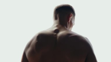 Kaslı bir adamın kaslarını esnetirken, spor salonunda güç ve zindelik gösterirken dikiz ayarı. Görüntü vücut geliştirmeyi, erkekliği ve fiziksel sağlığa bağlılığı vurguluyor..