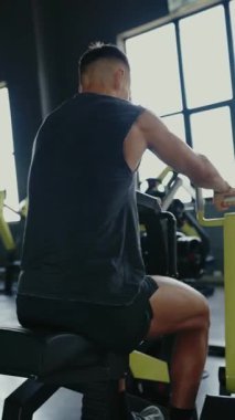 Spor aletleri üzerinde egzersiz yapan kaslı bir adam. Dayanıklılık, zindelik ve adanmışlık vurgulanıyor. Odaklanma ve yoğun çalışma seansı. Kas Adam Dikey