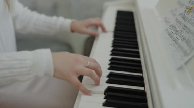 Eğitim ve öğrenim geliştirme konsepti. Müzik dersi veren genç bir müzisyen. Sessiz bir kişi dairesinde otururken piyano çalışır. Eller piyano tuşlarına basıyor..