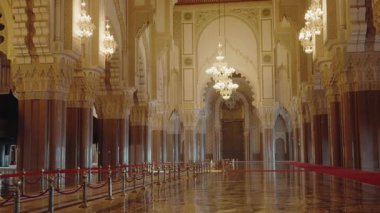 Kazablanka, Fas 'taki 2. Hasan Camii' nin büyük iç kesimi. Süslü sütunlar, kemerler ve kristal avizeler. Cilalı zemin ihtişamı yansıtıyor. Görkemli ve ruhani atmosfer.