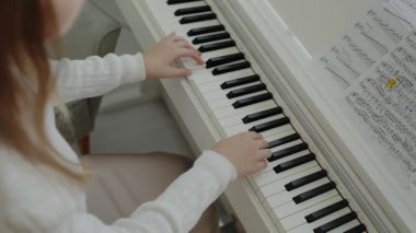 Genç kız evde piyano çalışıyor. Eğitim ve öğrenim geliştirme konsepti. Odaklanmış genç, güzel bir kız. Elektrikli piyano çalarak eğleniyor. Müzik dersi veren genç bir müzisyen..