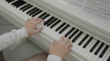 Genç kız evde piyano çalışıyor. Eğitim ve öğrenim geliştirme konsepti. Odaklanmış genç, güzel bir kız. Elektrikli piyano çalarak eğleniyor. Müzik dersi veren genç bir müzisyen..