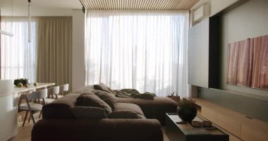 Rahat mobilyaları, geniş pencereleri ve doğal ışığı olan modern oturma odası. Sıcak, davetkar bir yer rahatlama ya da aile toplantıları için mükemmel. nötr renk paleti, minimalist tasarım.