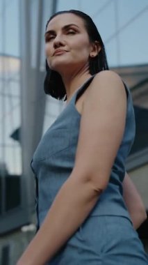 Mavi takım elbiseli kendine güvenen bir iş kadını modern bir ofis binasının önünde duruyor. İş dünyasında profesyonellik ve başarı yayıyor. Yavaş çekim onun güçlü varlığını arttırır..