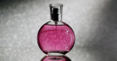 Göz kamaştırıcı bir görüntü pembe sıvıyla dolu yuvarlak bir parfüm şişesini sergiliyor, ışıl ışıl, bokeh bir arka plan üzerine kurulmuş. Güzellik, moda ya da güzel kokular için mükemmel. Zarif Pembe Parfüm Şişe