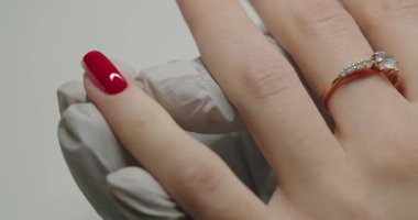 Lateks eldivenli kadın manikürcü kadın tırnaklarını kırmızı ojeyle kaplıyor. Kadın kuaför salonu ziyaretçisi tırnak ameliyatından sonra incelikli ve göze çarpan sonuçları bekliyor. Güzellik salonu. Kapat..