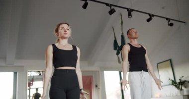 Erkek ve kadın birlikte yoga yapıyorlar. Çıplak ayaklı kadın ve erkeğin hafif stüdyodaki yoga seansı sırasında aşağı ve yukarı bakan köpek pozları çekimleri..