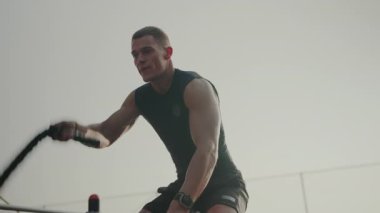 Paralel barlar üzerinde odaklanmış erkek atlet eğitimi. Genç, kararlı bir erkek atlet, paralel parmaklıklarda, açık ve sessiz bir arka plana karşı güç çalışması yapıyor..