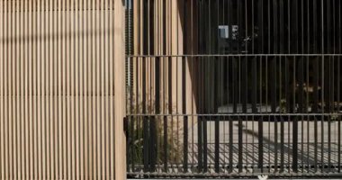 Ahşap panelli ve siyah metal çitli modern mimari. Güneş ışığı gölgeler yaratır. Şık ve minimalist tasarım. mimari, tasarım, gayrimenkul, yaşam tarzı ve kentsel yaşam.