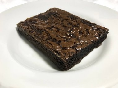Beyaz arka planda çikolata parçacıkları olan büyük bir brownie portresi.