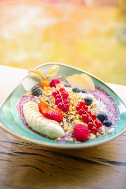 Acai smoothie bowl with strawberries, banana, blueberries, apple and granola on summer background. Breakfast bowl with fruit and cereal, close-up, top view, space for text