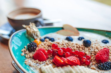 Delicious smoothie bowl with strawberries, banana, blueberries, apple and granola on summer background. Breakfast bowl with fruit and cereal, close-up, top view, space for text
