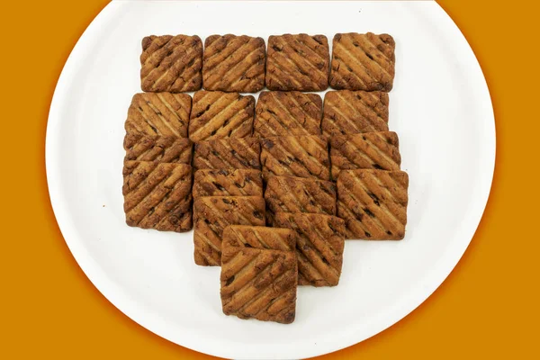 In White Plate Hide and Seek Biscuits, Isolated On Orange Background