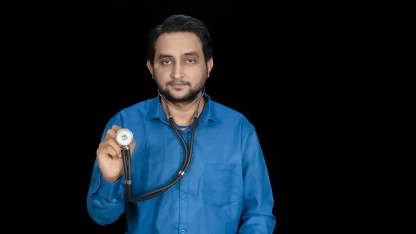 黒の背景に隔離された手に聴診器を保持している南アジアの若い男性医師 医療専門家の肖像 両側にスペースをコピー — ストック写真