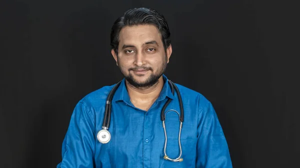 黒の背景に隔離された肩に聴診器を保持している南アジアの若い男性医師 医療専門家の肖像 両側にコピースペース — ストック写真