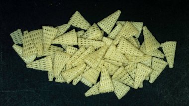 Üçgen şekilli Fryums çıtır çıtır atıştırmalıklar siyah arkaplanda