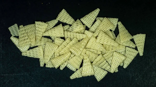 Üçgen şekilli Fryums çıtır çıtır atıştırmalıklar siyah arkaplanda