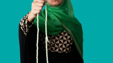 Bir elinde tasbeyle Allah 'a dua eden mü' min bir kız.
