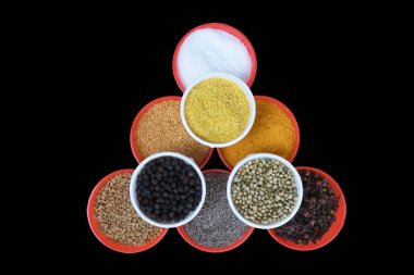 red bowls filled with salt, Fenugreek Seeds, turmeric powder, Mustard Seeds, Cumin Seeds, Clove, Yellow Split Mustard Seeds, Black Pepper, and Coriander Seeds, Isolated on Black Background clipart