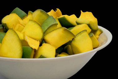 Mango turşusu için mango dilimlerinin beyaz kasedeki görüntüsü, siyah arka planda izole edilmiş.