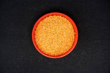 Genellikle Rai Kuria olarak adlandırılan Split hardal tohumlarının üst görüntüsü, kırmızı kasede kırılarak siyah arka planda izole edilmiş hardal tohumlarıdır.