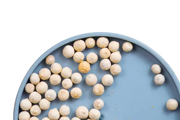 Stock image A mound of white peppercorn (white pepper) seeds isolated against a white background.