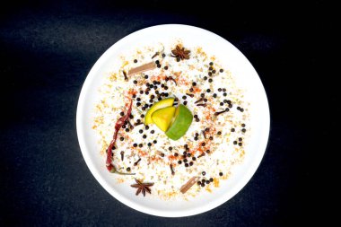 Mango turşusu, kırmızı biber, karabiber, karanfil, kakule, anason gibi Hint baharatlarının üst görüntüsü. Sarı plakalı, siyah arkaplanda izole edilmiş.